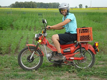 Mike Gretzinger sits atop his red Honda CT110 to pose for a photo between research plots at Farming Smarter in 2014.